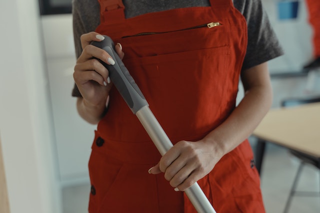 professional janitor in red overalls holding mop